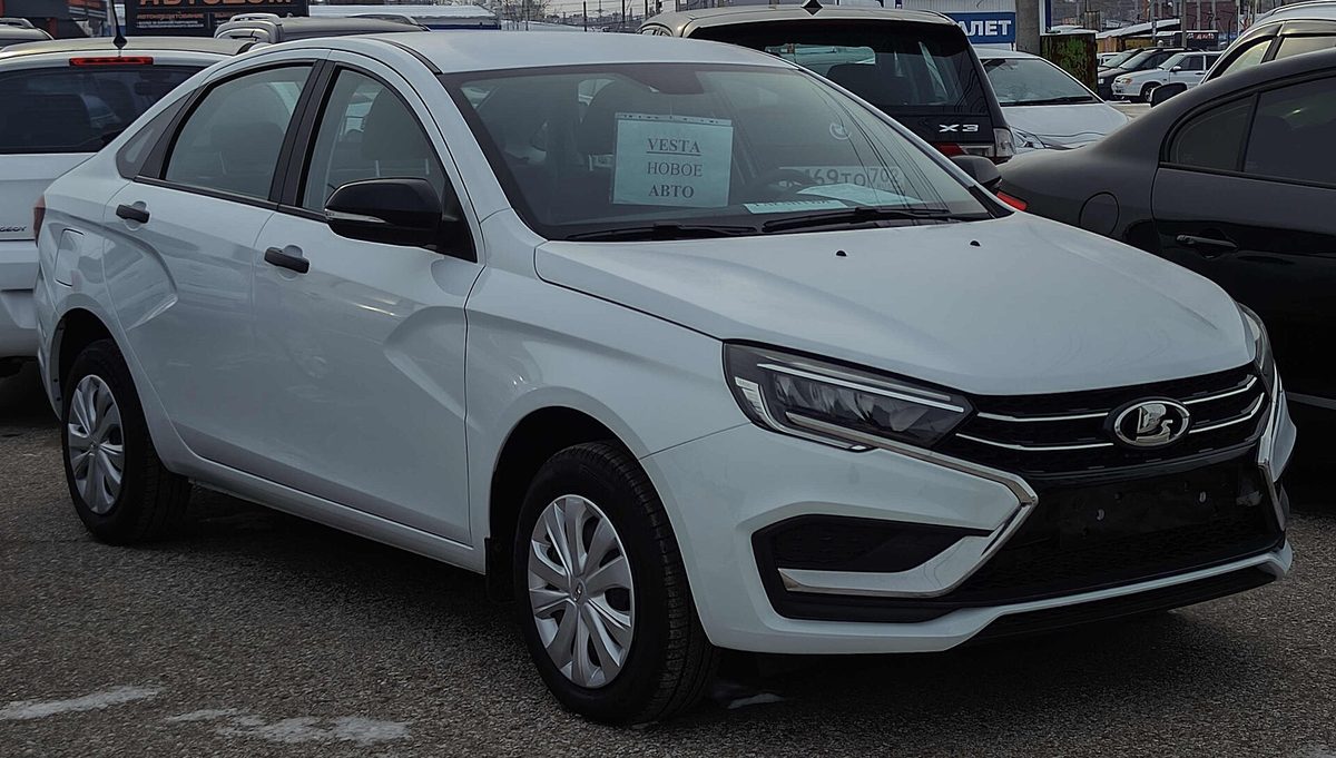 Новая белая Lada Vesta на площадке автодилера с табличкой «VESTA новое авто» — модель, которая чаще всего попадает под программу льготного автокредитования