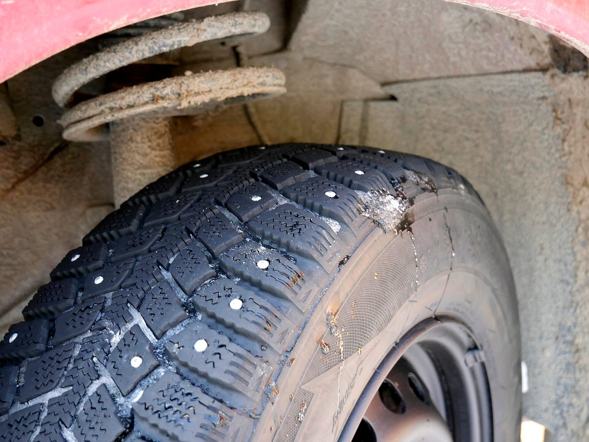 Шипованная зимняя шина, установленная на автомобиль, крупный план протектора с шипами
